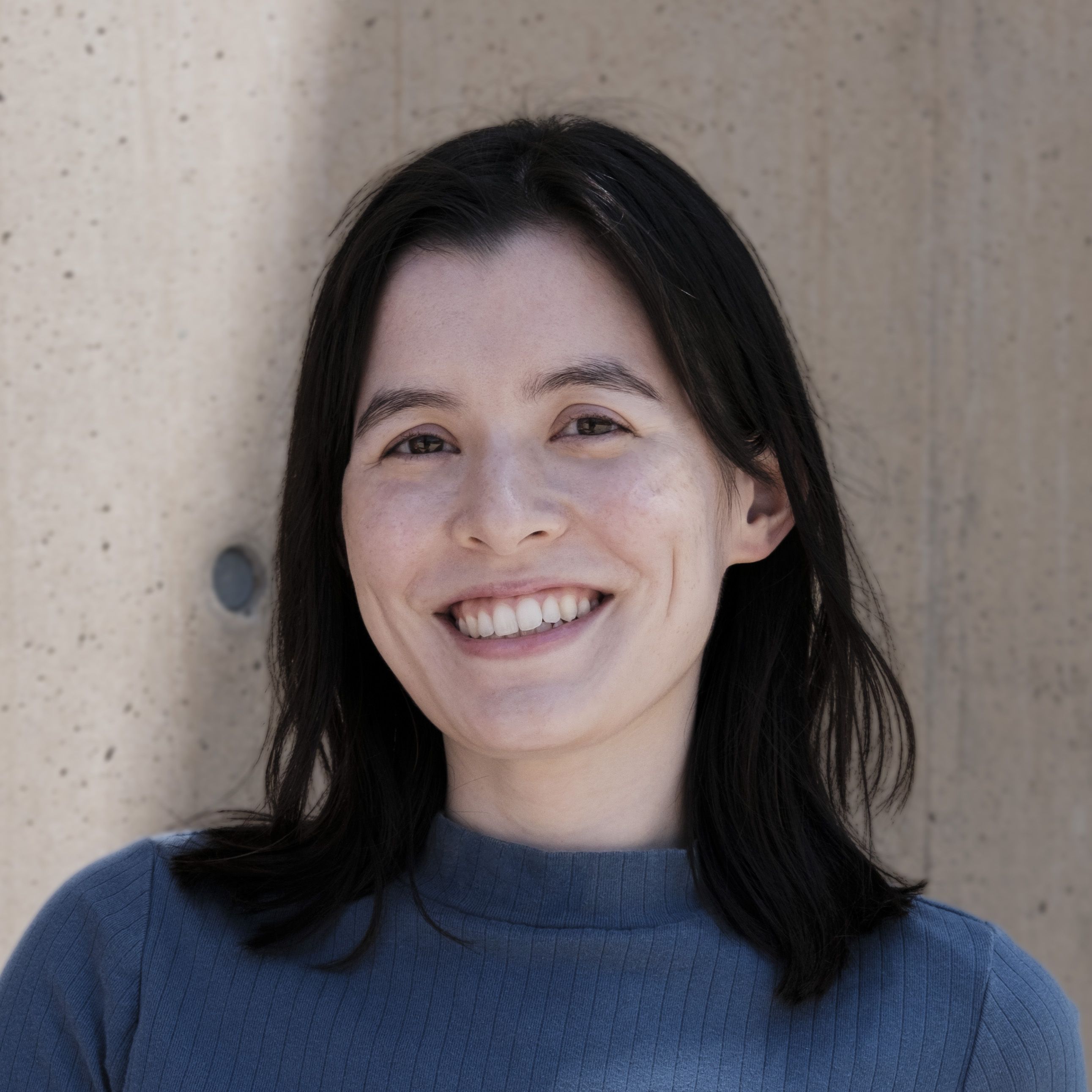 headshot of Rachael wearing blue in front of a beige wall
